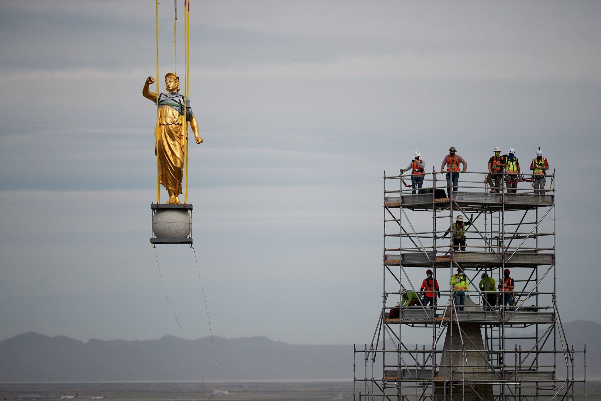 (photo courtesy The Church of Jesus Christ of Latter-day Saints) The angel Moroni and capstone being removed by a large crane with artisan journeyman viewing in the background as part of the ongoing renovation of the Salt Lake Temple, May 18, 2020.